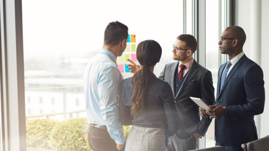 Diverse,Multiracial,Management,Team,Standing,Grouped,In,Front,Of,A